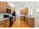 Traditional kitchen with wood cabinets, stainless steel and black appliances, tile backsplash, and hardwood floors at 3213 Kirby St, Durham, NC 27713