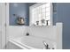 A modern, white bathtub is featured with a decorative window and white tile in this updated bathroom at 384 Rocky Run Ln, Lillington, NC 27546