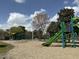 Vibrant playground with slide and swing set surrounded by trees under a partly cloudy sky at 416 Avery St, Garner, NC 27529
