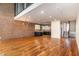 Open living room with hardwood floors, brick wall, modern lighting, and kitchen view at 4229 American Dr # F, Durham, NC 27705