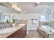 Bathroom featuring double sinks with granite counters, decorative mirrors, walk-in shower, and soaking tub at 4303 Thetford Rd, Durham, NC 27707