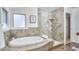 Luxurious bathroom featuring soaking tub with tile surround and a glass-enclosed shower with premium fixtures at 4303 Thetford Rd, Durham, NC 27707