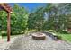 Backyard brick fire pit with a curved seating area, surrounded by mature trees and lush landscaping at 4303 Thetford Rd, Durham, NC 27707