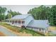 Home featuring an attached garage with red doors, a wraparound porch, and mature landscaping at 468 Loftis Loop Rd, Roxboro, NC 27574