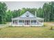 Inviting single-story home boasts a covered front porch, metal roof, and manicured lawn surrounded by mature trees at 468 Loftis Loop Rd, Roxboro, NC 27574