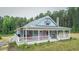 Welcoming single-story home with covered front porch and American flag displays country charm with mature trees in the background at 468 Loftis Loop Rd, Roxboro, NC 27574