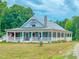 Charming home featuring a full wraparound porch, a stone chimney, and beautiful mature landscaping at 468 Loftis Loop Rd, Roxboro, NC 27574