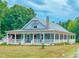 Charming home featuring a full wraparound porch, a stone chimney, and beautiful mature landscaping at 468 Loftis Loop Rd, Roxboro, NC 27574