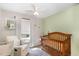 Inviting Bedroom with a light-green accent wall, white chair, and dark wood crib at 7708 Foxwood Dr, Raleigh, NC 27615