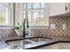 Kitchen detail with black faucet, white cabinetry, stainless steel sink, and designer backsplash at 7825 Breckon Way, Raleigh, NC 27615