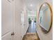 Inviting hallway with wood flooring, white walls, and a decorative mirror at 804 Windmill Palm Dr, Zebulon, NC 27597