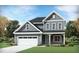 Charming two-story home featuring gray siding, stone accents, an attached garage, and a well-manicured lawn at 937 Thimbleweed Way, Wake Forest, NC 27587