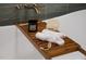 Close-up of a luxurious bathtub tray with towels, candle and bath sponge at 1008 North St, Durham, NC 27701