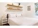 Modern bedroom with white bedding, floating shelves and stylish decor at 1008 North St, Durham, NC 27701