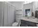 Well-lit bathroom featuring granite countertops, a gray shower curtain, and ample storage on wall shelves at 1207 Bluewater Way, Durham, NC 27703