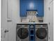 Laundry room with blue cabinets, gray tile backsplash, and modern washer and dryer units at 1207 Bluewater Way, Durham, NC 27703