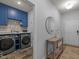 Open-concept laundry room with matching washer and dryer, overhead cabinets, and designer-selected decorative items at 1207 Bluewater Way, Durham, NC 27703