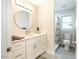 This modern bathroom features a white vanity with stone countertop, a round mirror, and a walk-in shower at 122 W Union St, Hillsborough, NC 27278