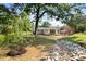 Lovely backyard with a deck featuring a table set, mature trees, landscaping, and a rock feature at 122 W Union St, Hillsborough, NC 27278
