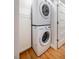 This modern laundry area features a stacked washer and dryer with wooden floors and white cabinets at 122 W Union St, Hillsborough, NC 27278