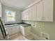 Laundry room with gray counters, white cabinets, utility sink, and decorative flooring at 1309 Sanctuary Pond Dr, Raleigh, NC 27603