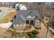 Aerial view of a home with beautiful stone and siding, a gray roof, and mature trees at 150 Lystra Ridge Rd, Chapel Hill, NC 27517