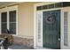 Elegant front door with wreath, sidelight, and nearby bench seating on a covered porch at 150 Lystra Ridge Rd, Chapel Hill, NC 27517