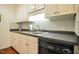 A kitchen with white cabinets, black appliances, and grey backsplash at 1808 W Cotton Gin Dr, Clayton, NC 27527