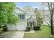 Two-story home with a two-car garage, cream siding, blue shutters, mature trees, and landscaped front yard at 206 Newberry Ln, Durham, NC 27703