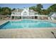 Community pool with a white clubhouse, clear blue water, surrounded by trees and a security fence at 206 Newberry Ln, Durham, NC 27703