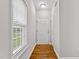 Well-lit hallway with hardwood flooring and neutral walls, leading to a bright entry door and side window at 2100 Thornblade Dr, Raleigh, NC 27604