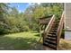 View of backyard with wooden deck and stairs leading to a spacious grassy area surrounded by lush greenery at 309 Watson St # A/B, Creedmoor, NC 27522