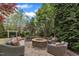 Outdoor patio boasts an in-ground firepit and matching cushioned furniture in a fully landscaped yard at 317 Briarfield Dr, Apex, NC 27502