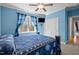 Blue bedroom with a ceiling fan, large window with blue curtains and wall mounted television at 3220 Brassfield Rd, Creedmoor, NC 27522