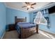 Comfortable blue bedroom features a large bed with dark wood frame, ceiling fan and window at 3220 Brassfield Rd, Creedmoor, NC 27522