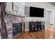 Cozy living room features a stone fireplace, hardwood floors, and a sleek modern TV at 3220 Brassfield Rd, Creedmoor, NC 27522