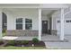 Inviting covered porch with brick accents, columns, and manicured landscaping leading to the front entrance at 3849 Rosebush Dr, Zebulon, NC 27597