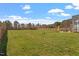 A large grassy backyard enclosed by a wooden fence with mature trees visible in the background at 45 Melody Dr, Youngsville, NC 27596