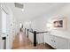 Bright hallway with hardwood floors, white walls, dark wood banister, and stylish white console table with accent lamp at 5004 Lakemont Dr, Raleigh, NC 27609