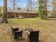 Expansive backyard with a fire pit, seating, mature trees, and a deck for outdoor enjoyment at 5130 Guess Rd, Durham, NC 27712