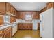 Traditional kitchen with wooden cabinets, white appliances, and vintage-style flooring at 5130 Guess Rd, Durham, NC 27712