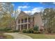 Brick home with a two-story porch, a curved driveway, lush landscaping, and blue sky at 5521 Erinvale Ct, Holly Springs, NC 27540