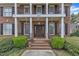 Close-up of home's front entrance showing brick stairs, columns, and manicured bushes at 5521 Erinvale Ct, Holly Springs, NC 27540