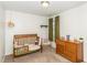Cozy bedroom with a wooden crib, dresser, neutral carpet, and a window with verdant curtains at 733 Frosty Way, Zebulon, NC 27597