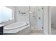 Bright bathroom with soaking tub, walk-in shower with glass enclosure, and white tile at 8117 Fergus Ct, Wake Forest, NC 27587