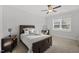 Cozy bedroom featuring a wooden bed frame, ceiling fan, carpet, and a desk area with a vanity and natural light at 8117 Fergus Ct, Wake Forest, NC 27587
