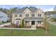 Elegant two-story brick home featuring a covered front porch, manicured lawn, and symmetrical window placement at 8117 Fergus Ct, Wake Forest, NC 27587