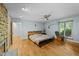 Comfortable bedroom with a ceiling fan, hardwood floors, stone fireplace, and bright natural light at 8805 Leesville Rd, Raleigh, NC 27613