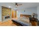 Relaxing bedroom featuring a stone fireplace, ceiling fan, and hardwood floors at 8805 Leesville Rd, Raleigh, NC 27613