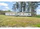 Expansive backyard with lush green grass and mature trees, and white house at 8917 Fowler Rd, Zebulon, NC 27597